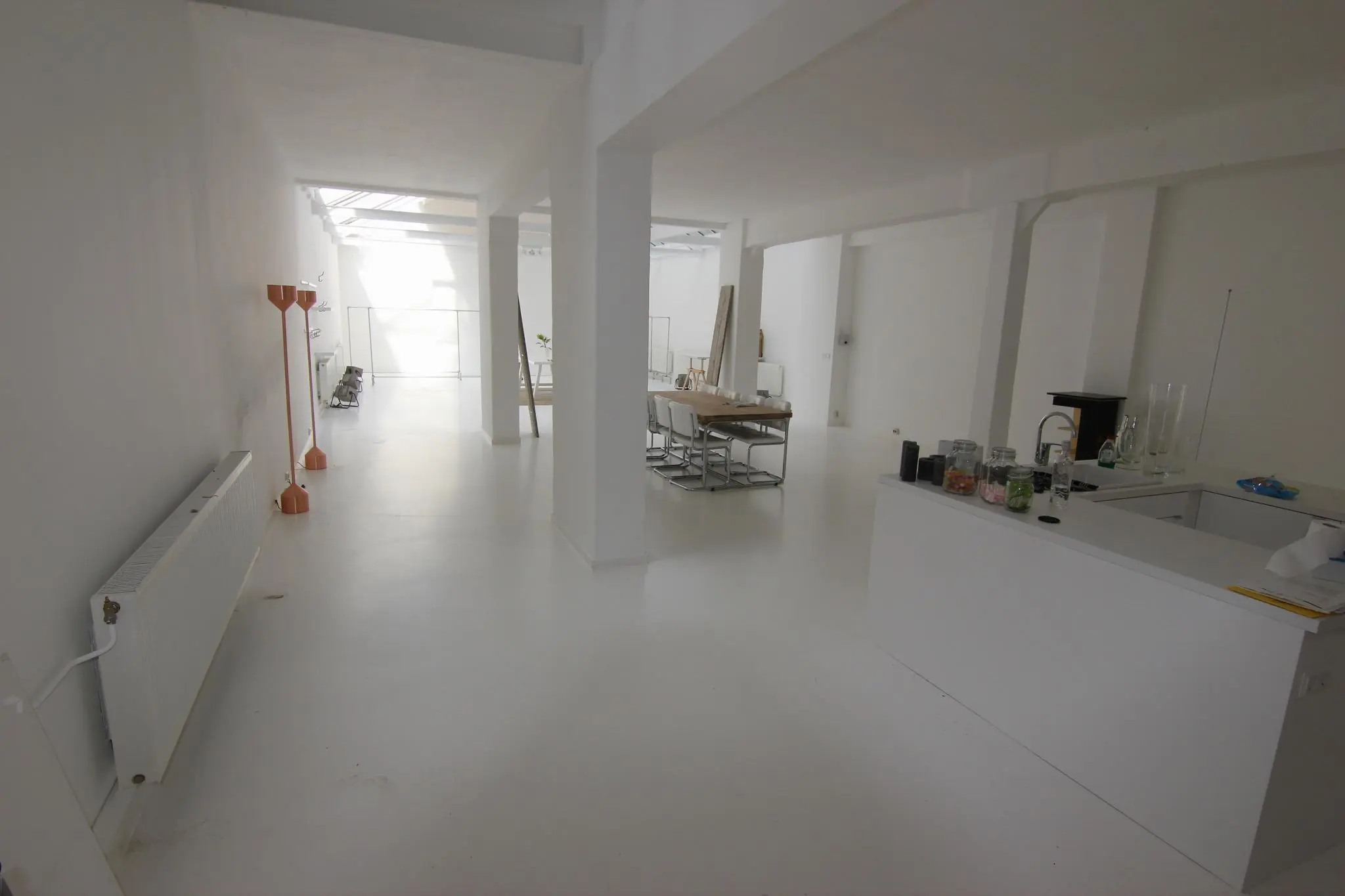 Licht en minimalistisch ingericht interieur van een open woonruimte aan de Graaf Florisstraat met keuken, eettafel en werkplekken.